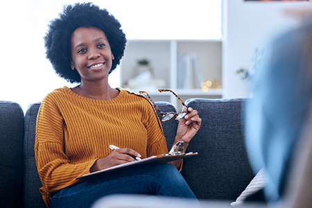 Black psychologist writing notes with patient